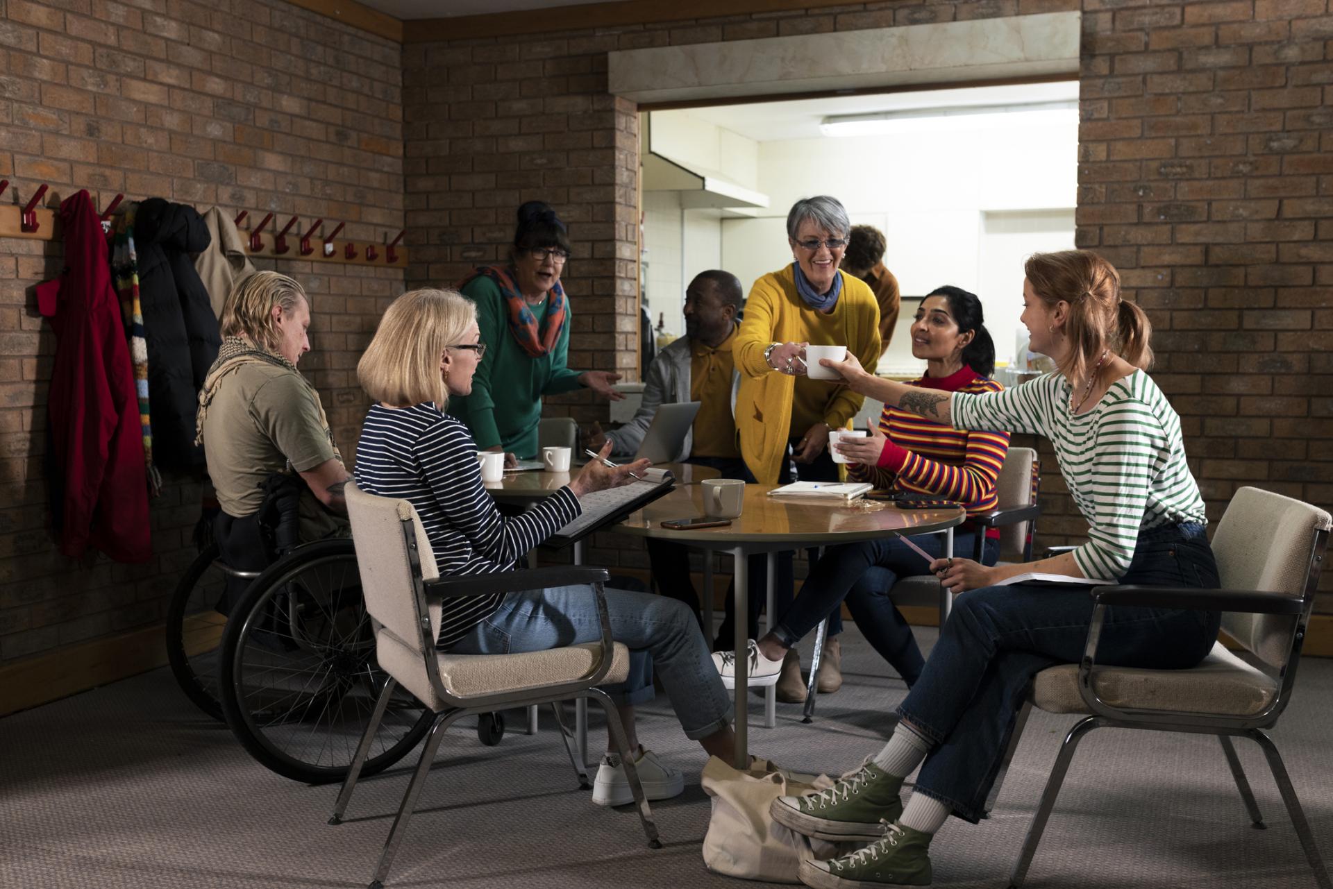 Group of volunteers hosting a meeting about their community. They are a diverse group and are all talking together, organising community events.