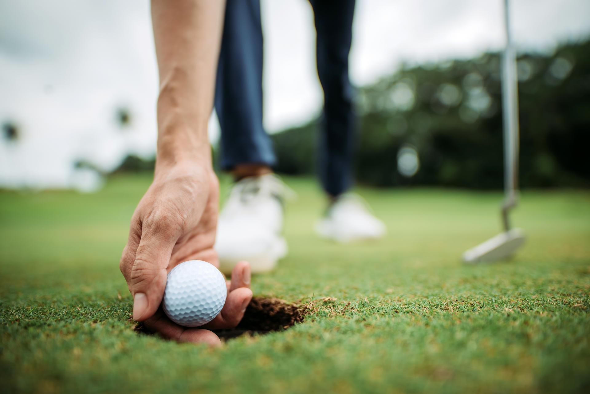 Bend over to take out the golf ball with hand