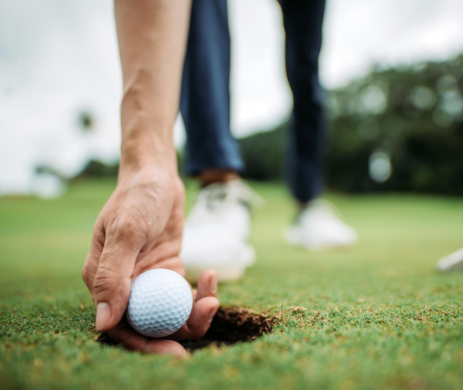 Hand picking up a golf ball